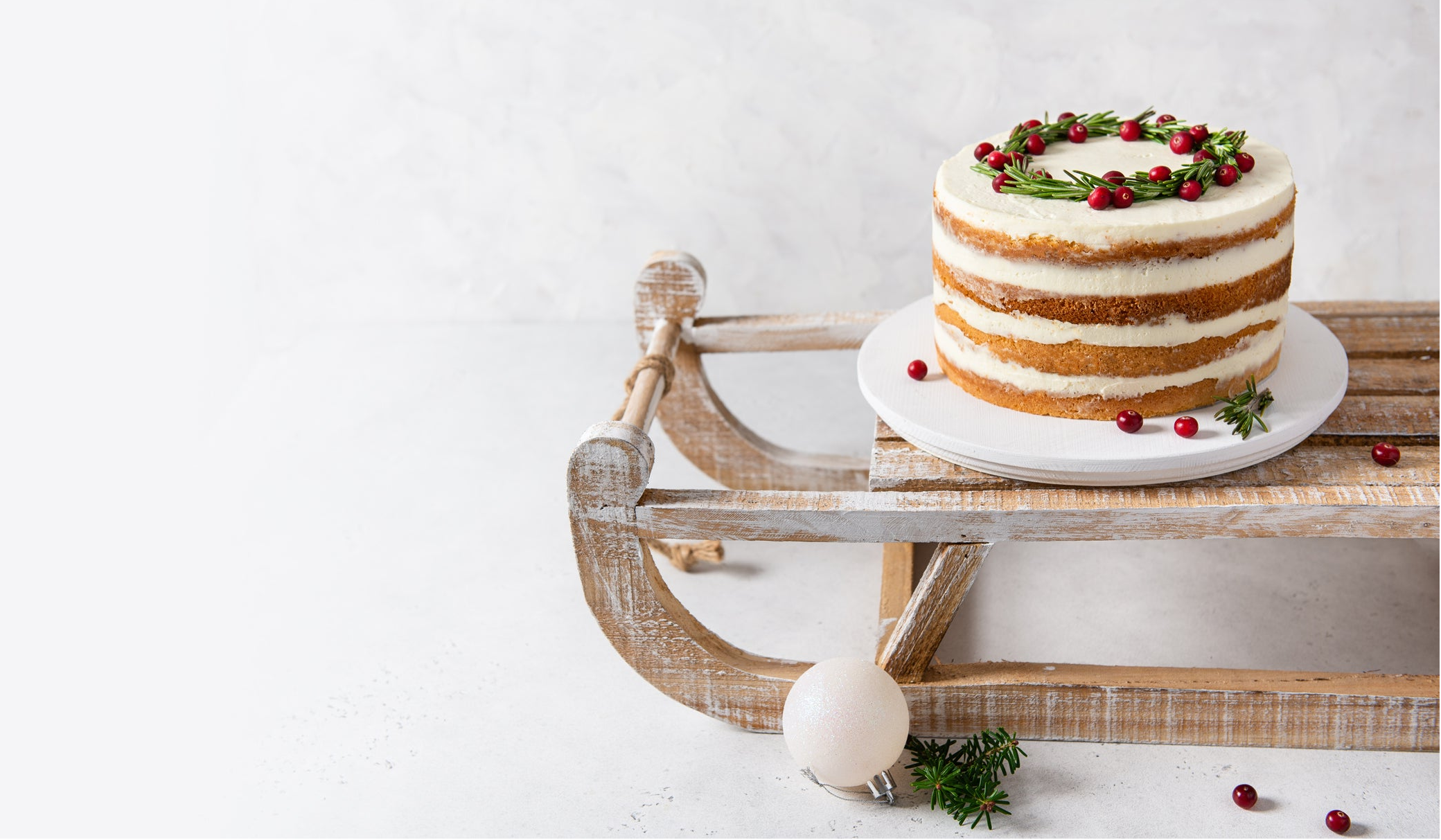 Naked cake with berries on a wooden sled against a white background