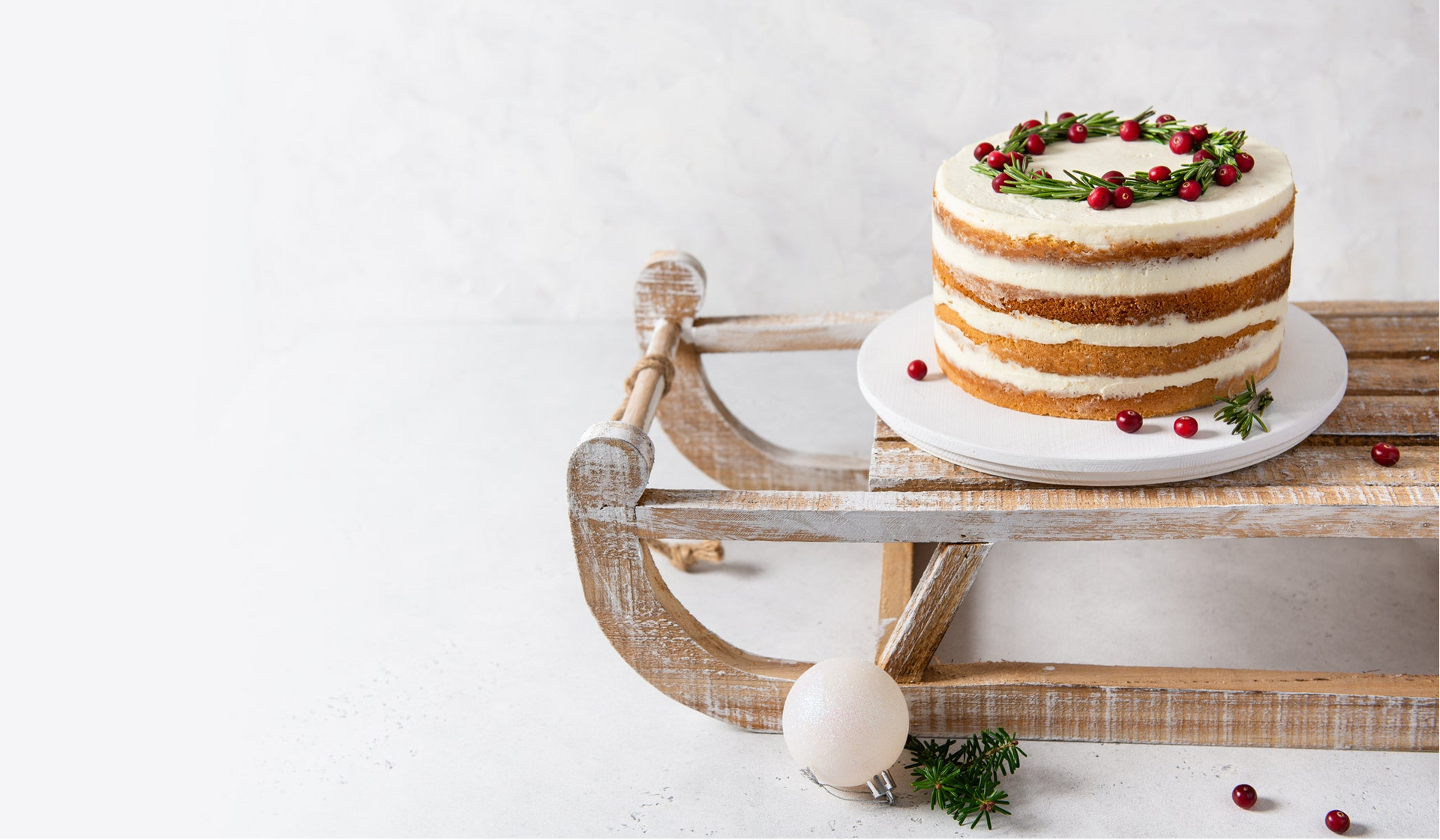 Naked cake with berries on a wooden sled against a white background